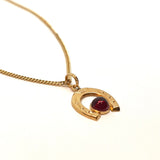 Horseshoe pendant with red stone